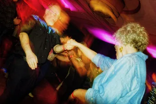 Dancers swirling in motion blur under colored lights at a Wintergrass late-night dance