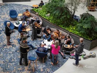 Overhead view of an acoustic jam circle of fiddle and guitar players in the hotel atrium garden at Wintergrass
