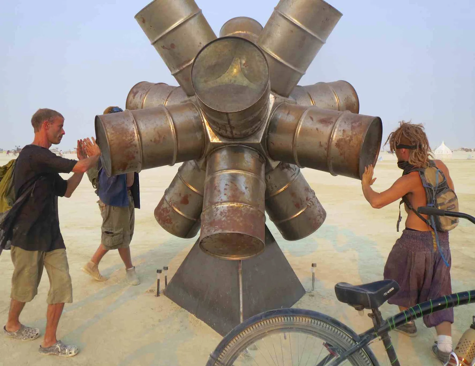 Costumed participants drumming around a rotating art piece at Burning Man