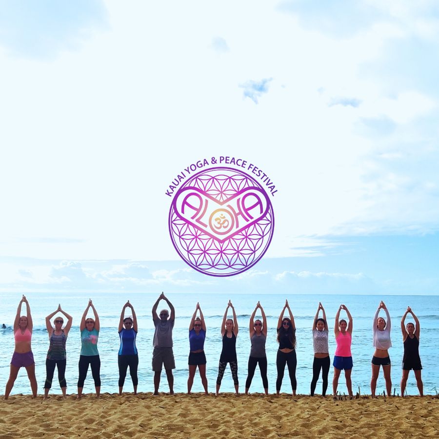 Festival-goers raise joined hands in a line on the beach beneath the ALOHA festival logo