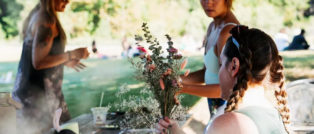 Festival-goers arranging dried-flower bouquets at a picnic table workshop at Flow Fest