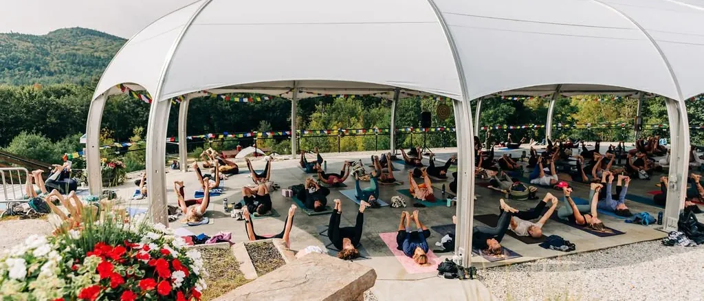 Outdoor class under the white domed pavilion with prayer flags at Kula Yoga Fest