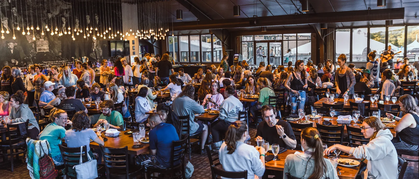 Festival-goers share dinner under Edison bulbs in the Montage Mountain lodge at NEPA Yoga Festival