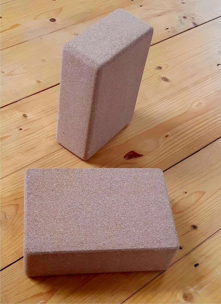 Two cork yoga blocks on a wooden floor