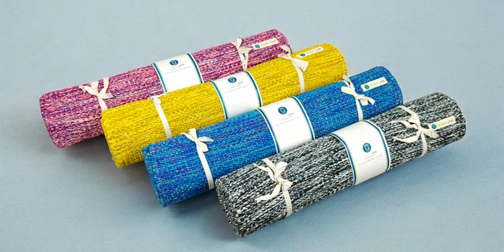 Four rolled cotton yoga mats in pink, yellow, blue and black