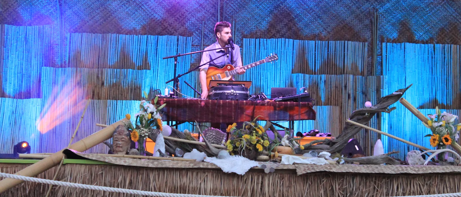 Guitarist on the bamboo-and-thatch decorated stage at Sangha Yoga Fest