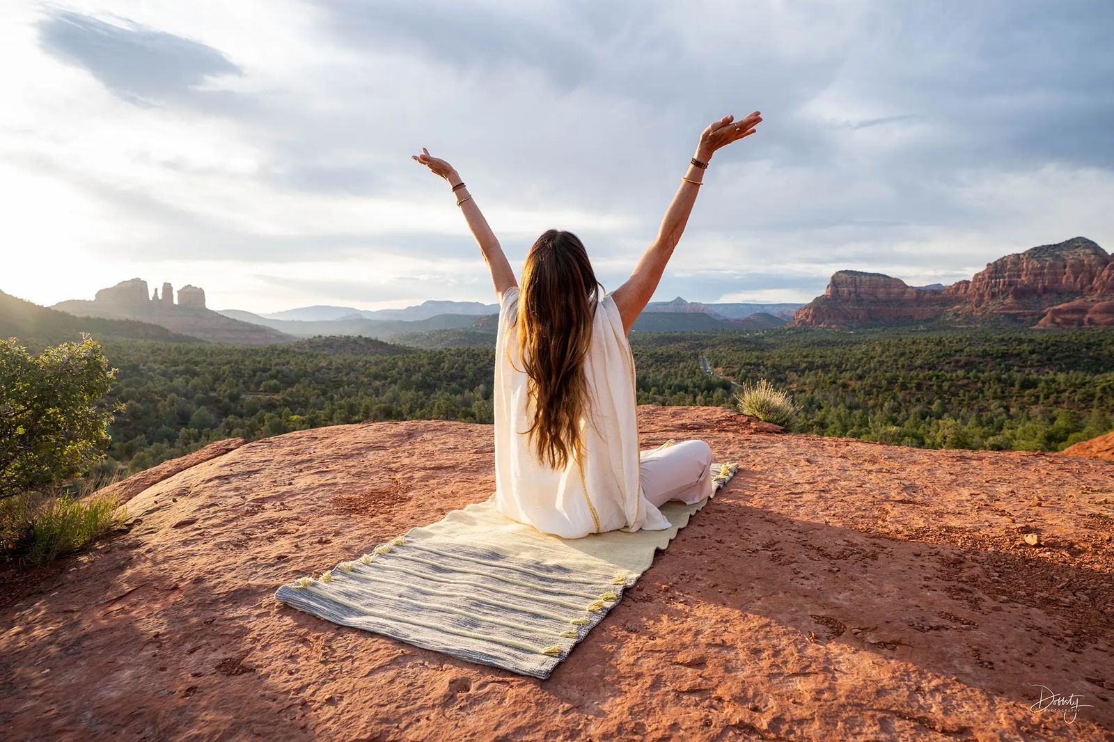 Practitioner with arms raised on a red-rock overlook above Sedona at Sedona Yoga Festival