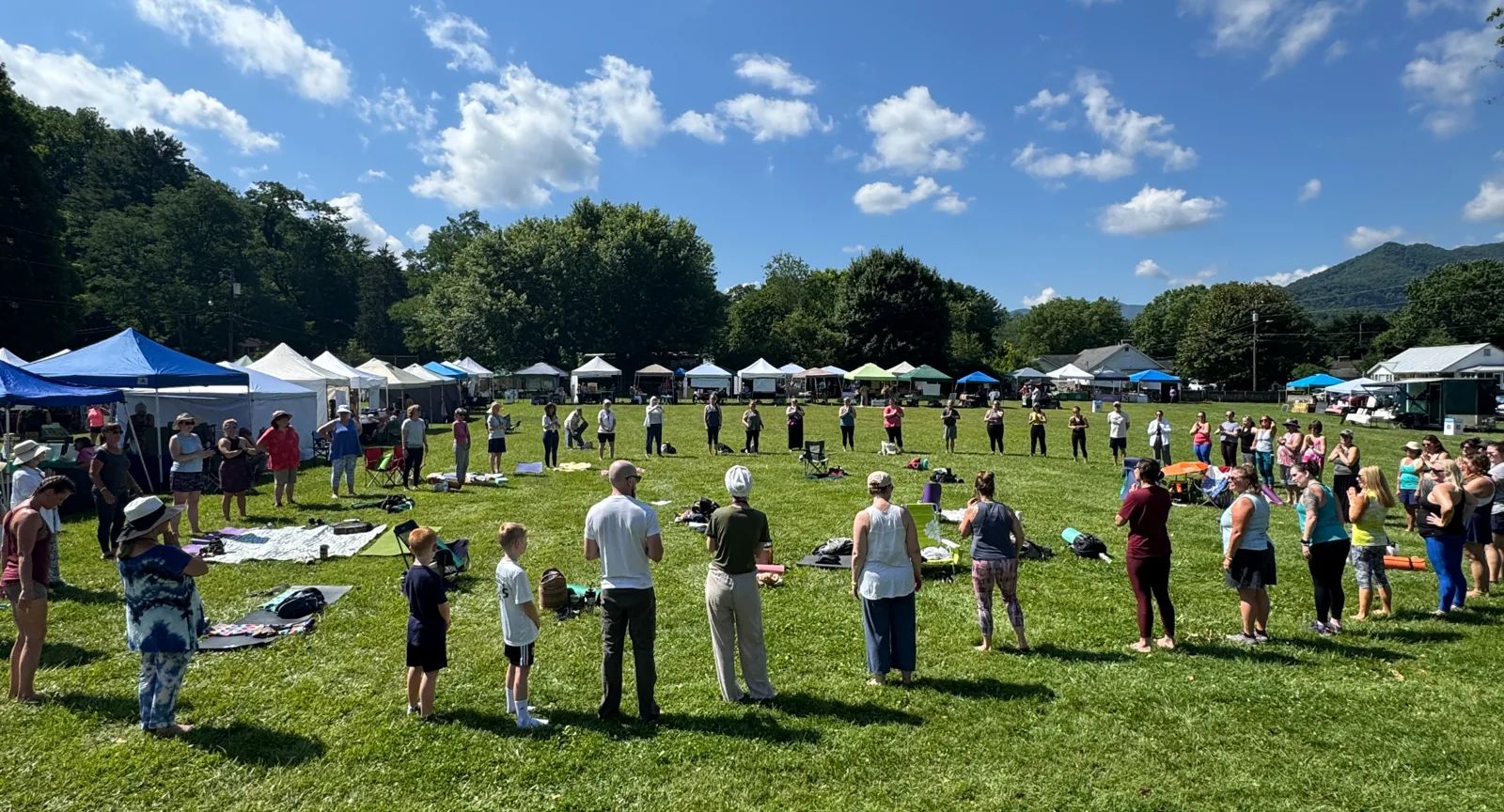 Opening circle on the festival field ringed by vendor tents beneath the Smokies