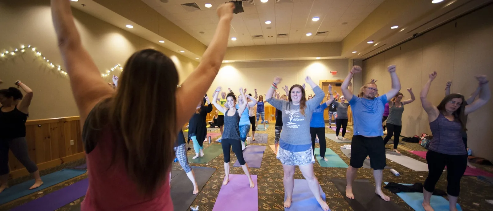 An energetic indoor class raises fists mid-flow at Yoga on the Mountain