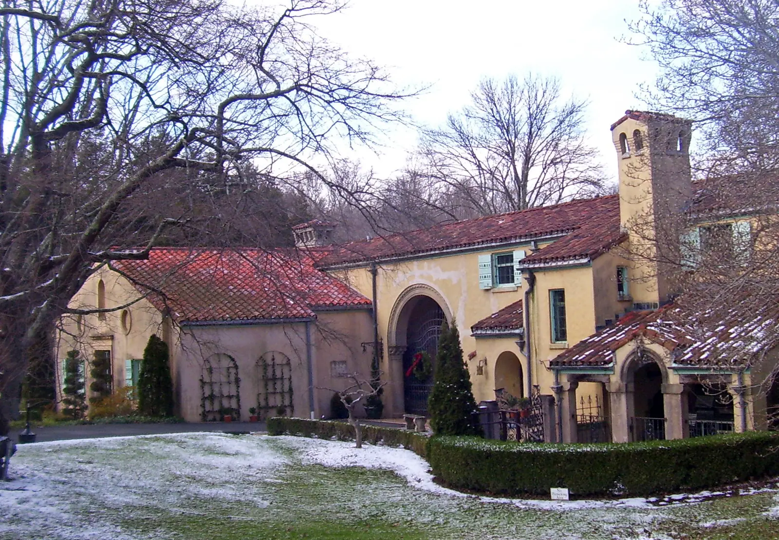Stucco buildings and the bell tower at Caramoor, seen across the lawn in winter