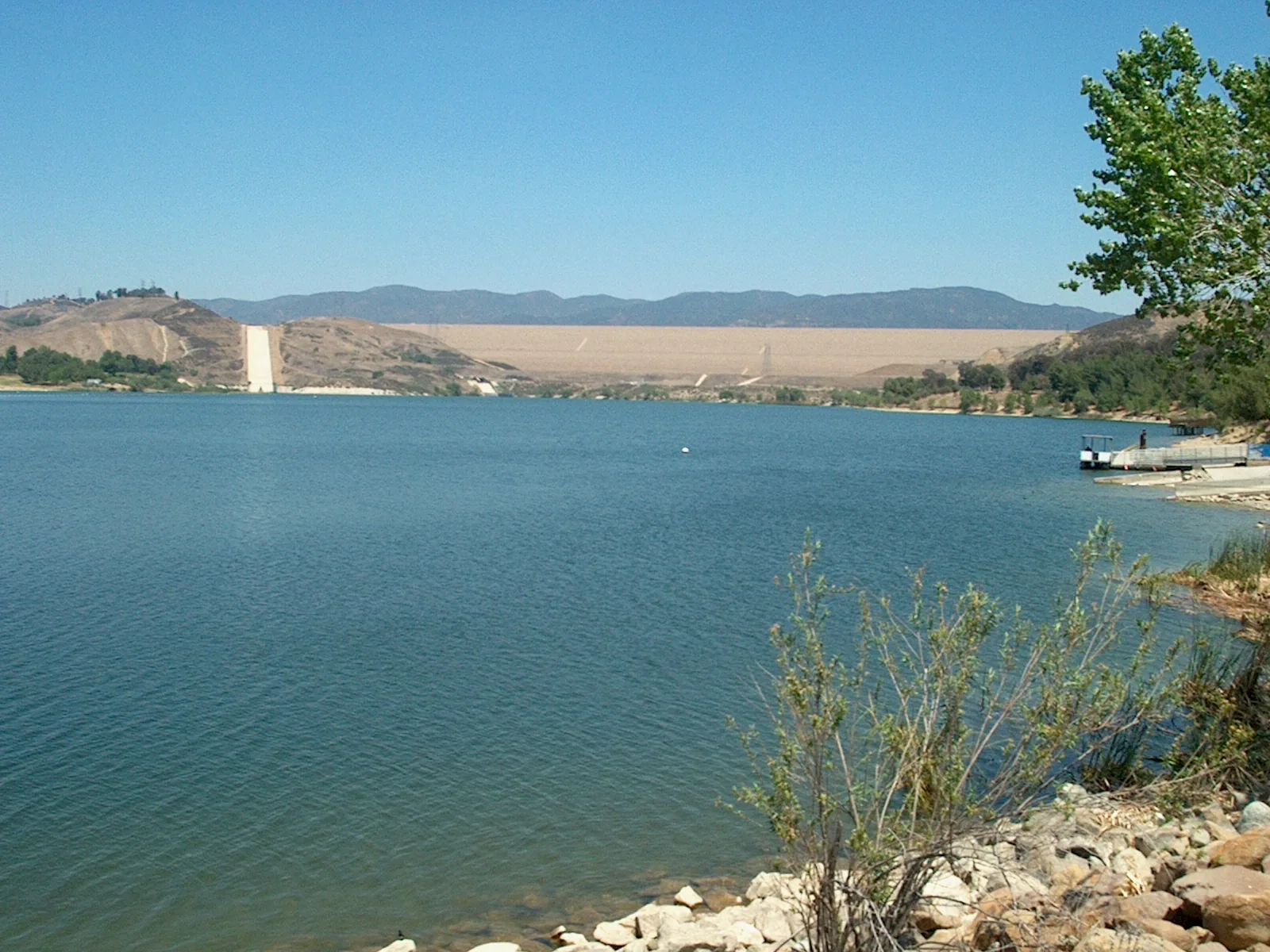 Castaic Lake seen from the shore, with the dam and dry hills beyond