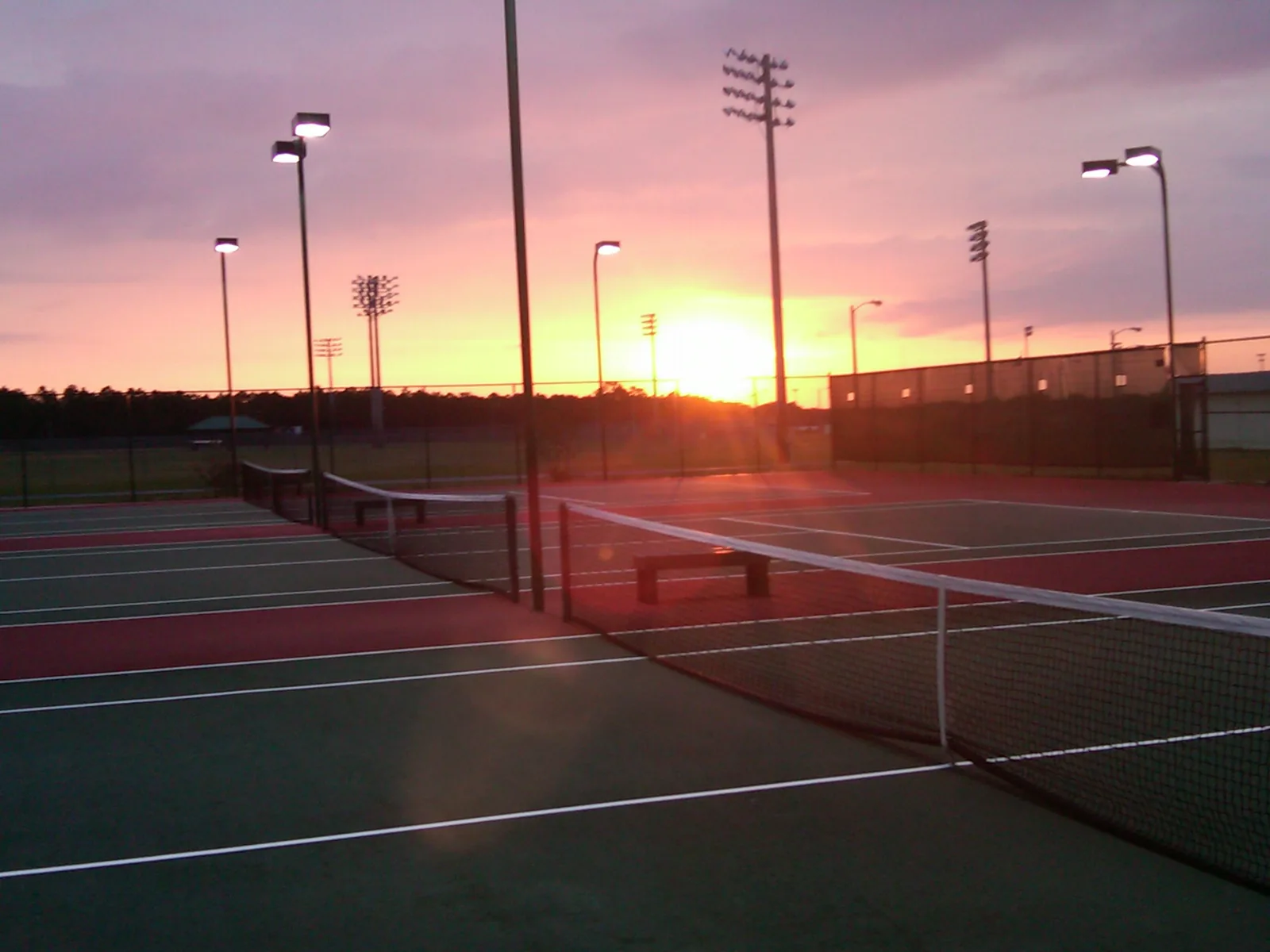 Floodlit tennis courts at Frank Brown Park at sunset